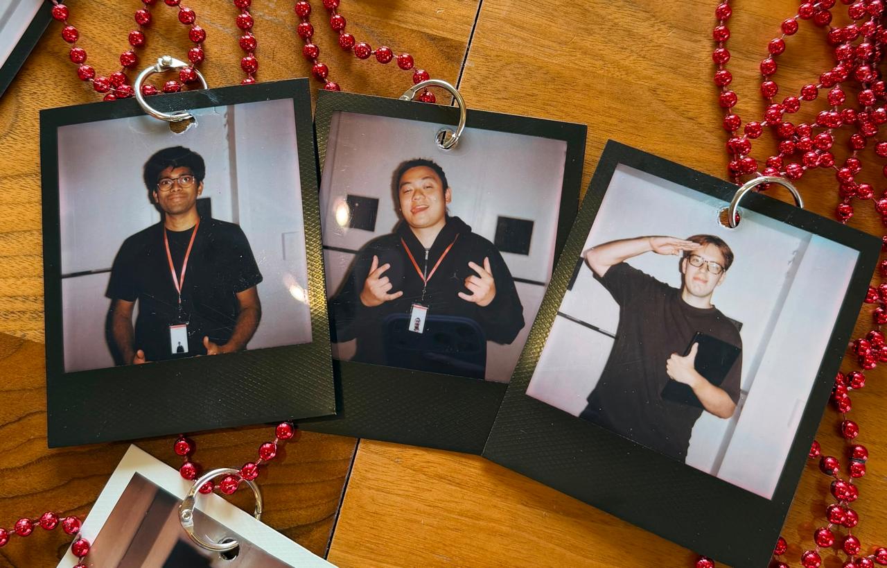 Three instant-film portraits of the Clusy founders laid on a wooden table, linked by red beads