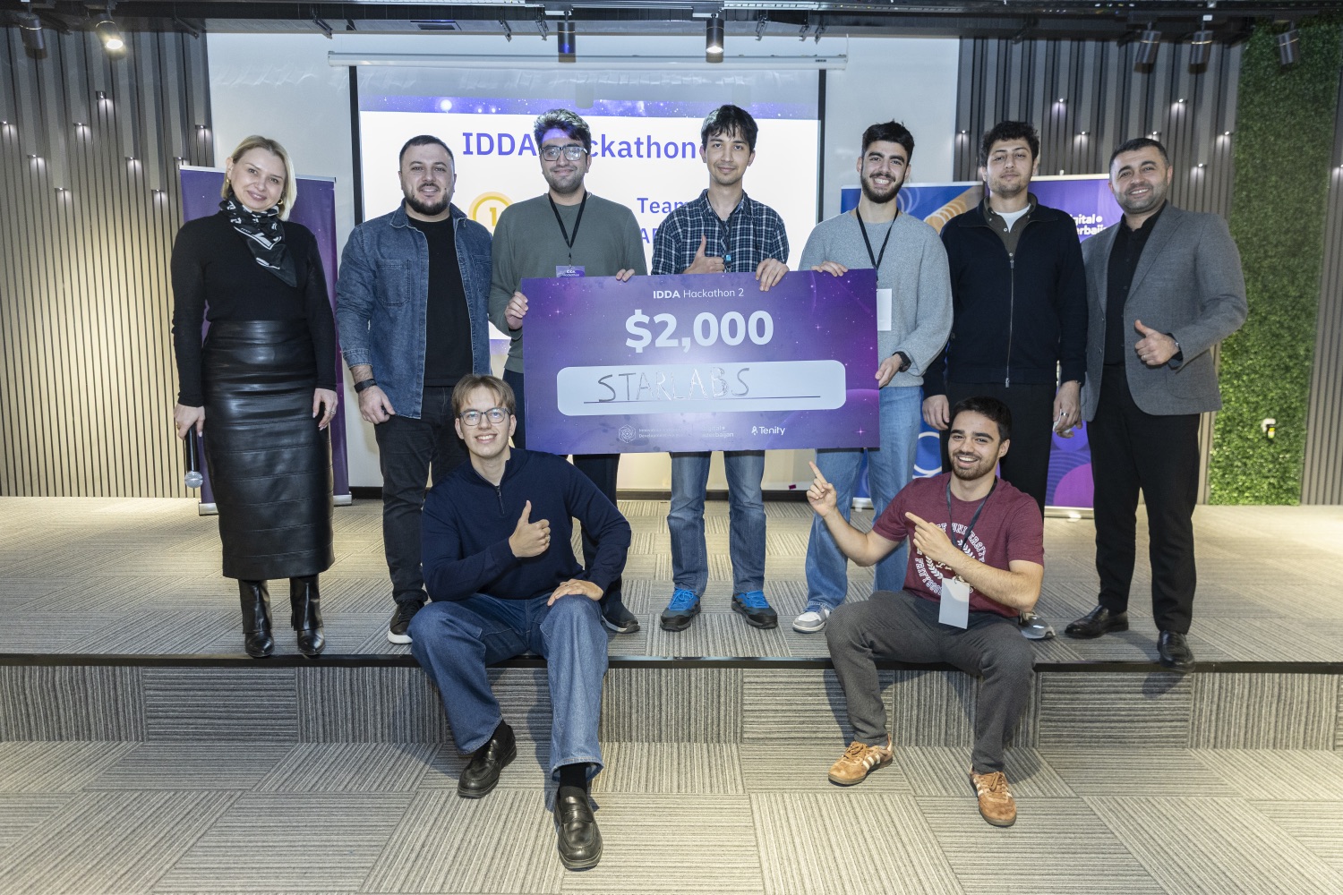 Nine people on a stage holding a large novelty cheque for two thousand dollars made out to team StarLabs, at IDDA Hackathon 2